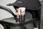 Tinkafu® 2-i-1 koppholder og mobilholder festet på barnevogn, viser hvordan drikke og mobil holdes trygt og lett tilgjengelig på trilletur i all slags vær.